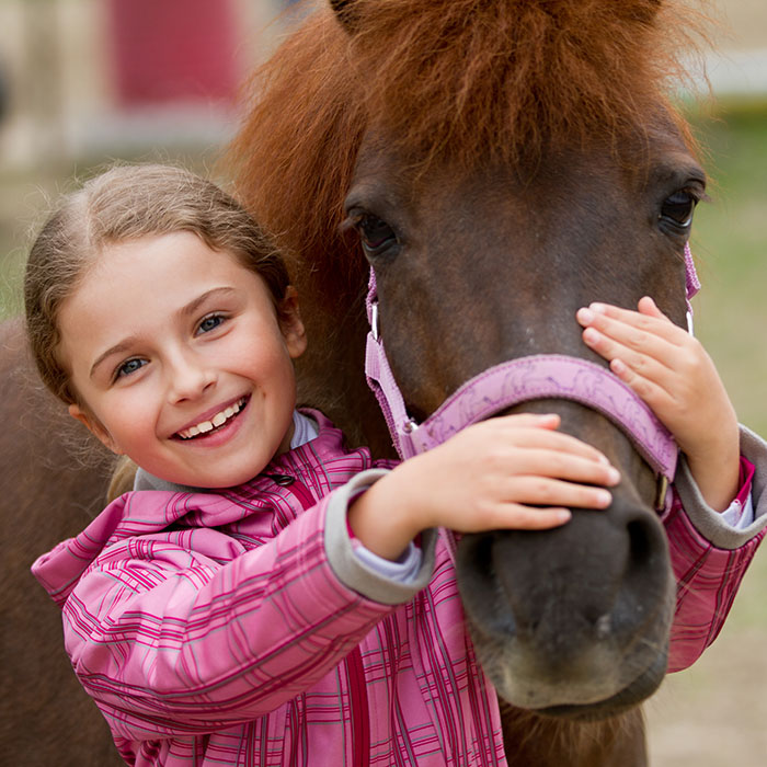 Kleines Mädchen hält einen Pferdekopf